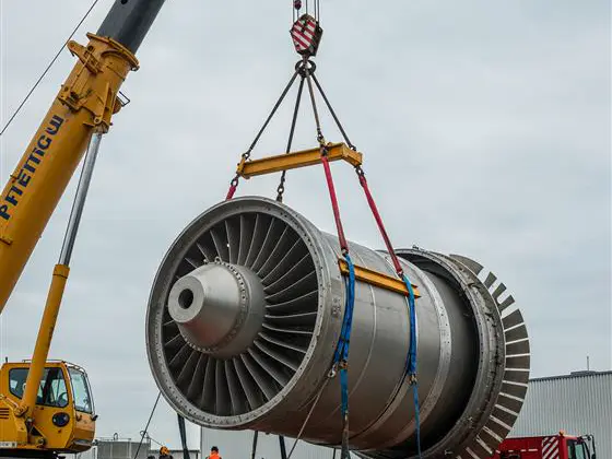 Grúa levantando una turbina sobre un camión cama baja